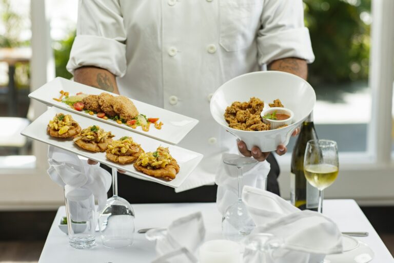 A chef in white dress shirt holding white ceramic bowl with food