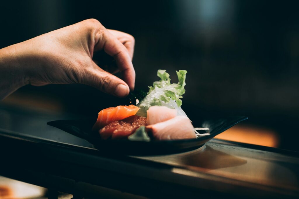 chef's left hand picking vegetable on plate